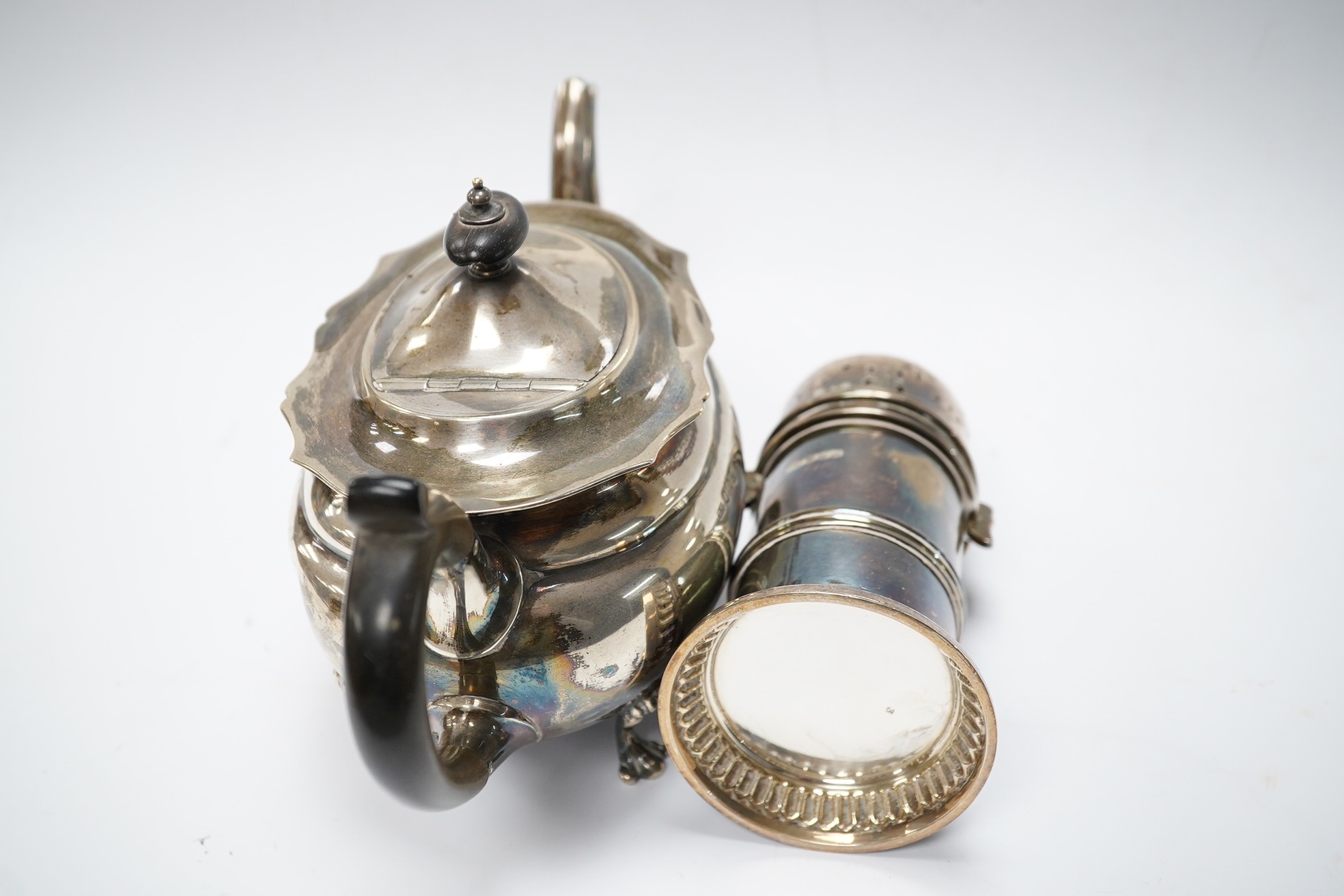 An Edwardian bachelor's silver teapot, Henry Wigful?, Sheffield, 1903, together with a George V silver lighthouse sugar caster by Atkin Brothers, 15.4cm, gross weight 19.5oz. Condition - poor to fair